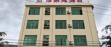 A multi-story building with a flat facade, multiple windows, and a sign at the top.