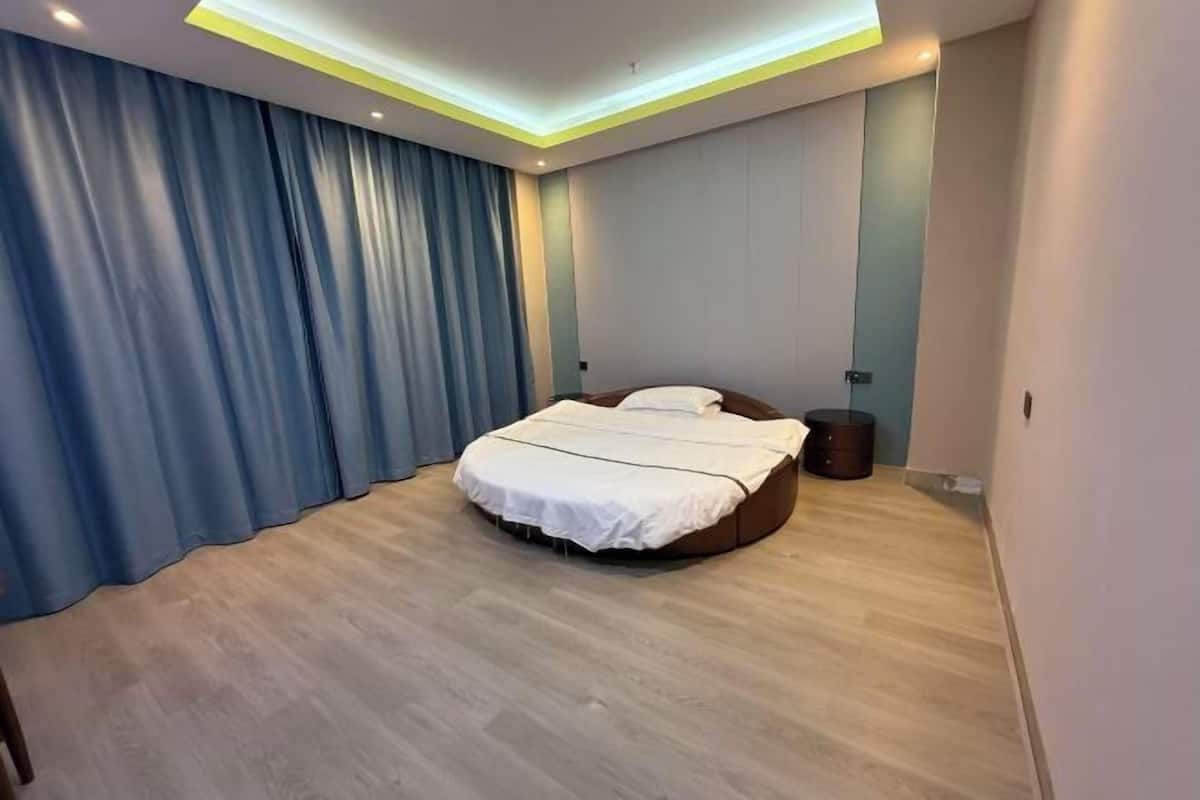 A modern bedroom with a round bed, a bedside table, and a nightstand.