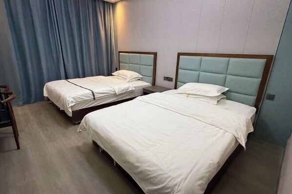 Habitación de hotel con dos camas individuales, una silla de madera y una cortina azul.