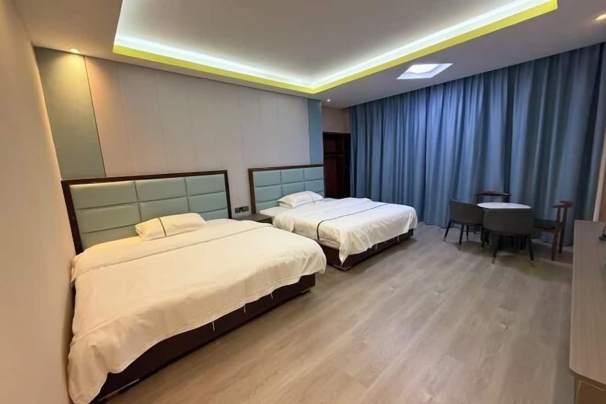 A hotel room with two beds, a desk, and a chair.