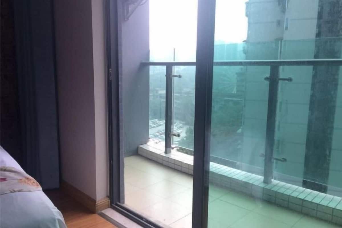Una habitación con cama, ventana y balcón con puerta de vidrio.