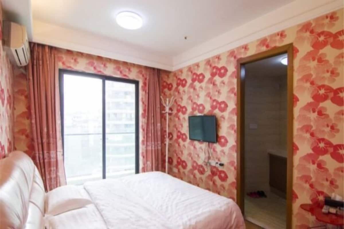 Habitación de hotel con cama, televisión montada en la pared y puerta corredera hacia el baño.