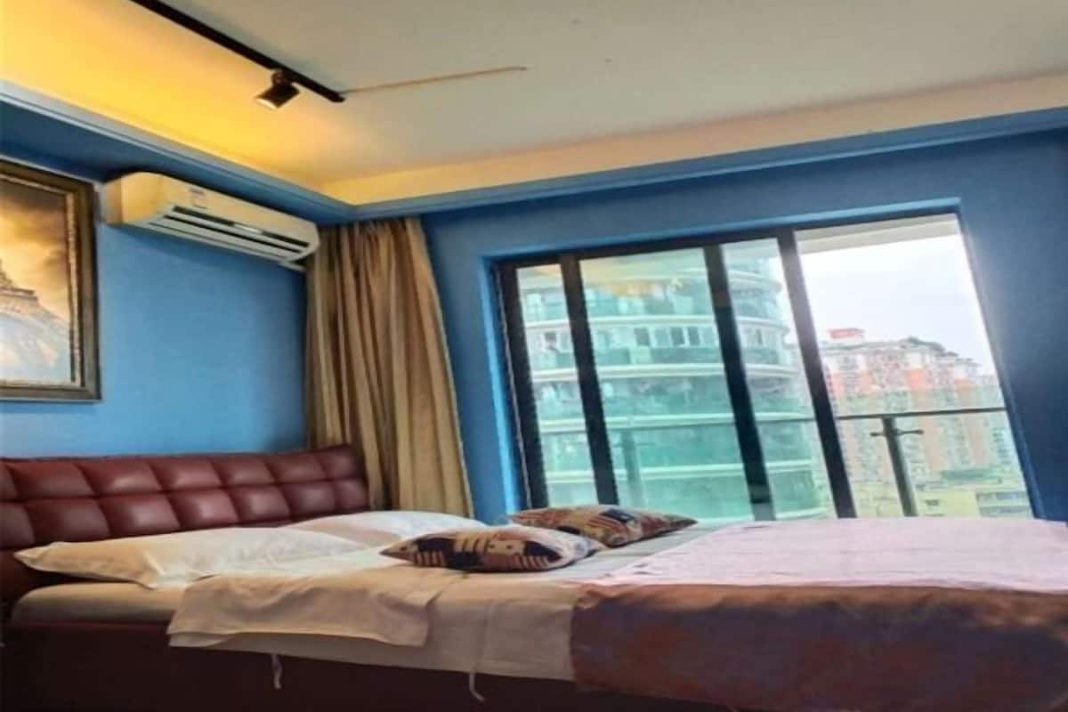 Habitación de hotel con cama, aire acondicionado y una ventana grande con vistas a la ciudad.