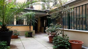 A courtyard with potted plants and a building with large windows. - A PARISIAN LOFT LOCATED JUST FEW MINUTES FROM RUE MONTORGUEIL (Paris)