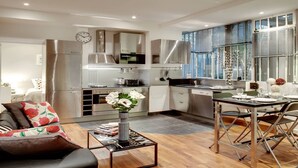 A modern kitchen with stainless steel appliances, a dining area with a table set for two, and a living area with a sofa and a coffee table. - A PARISIAN LOFT LOCATED JUST FEW MINUTES FROM RUE MONTORGUEIL (Paris)