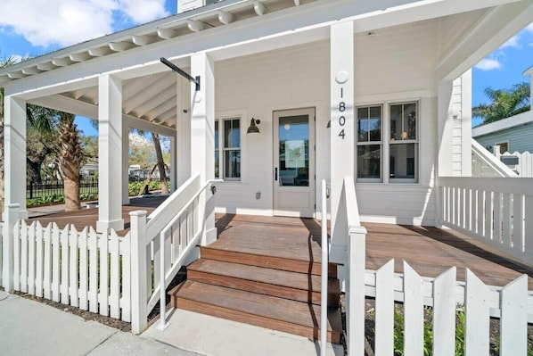 Stroll up to the charming front porch, featuring a wooden staircase and white picket fence.