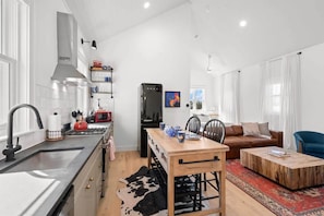 Une cuisine moderne avec un îlot central, un coin repas avec une table en bois, un canapé et une table basse.