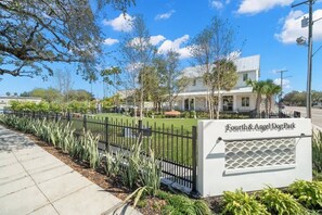 A sign for Fourth & Angel Dog Park with a paved walkway and a fence.