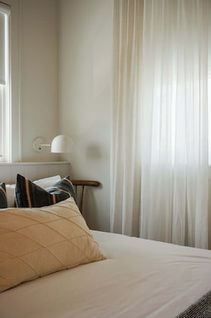 Un lit bien fait, avec un oreiller matelassé et une tête de lit blanche sobre.