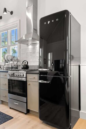 Cocina moderna con campana extractora de acero inoxidable, refrigerador negro y estufa a gas.