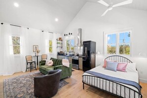 Una habitación amplia con cama, escritorio, silla y kitchenette.