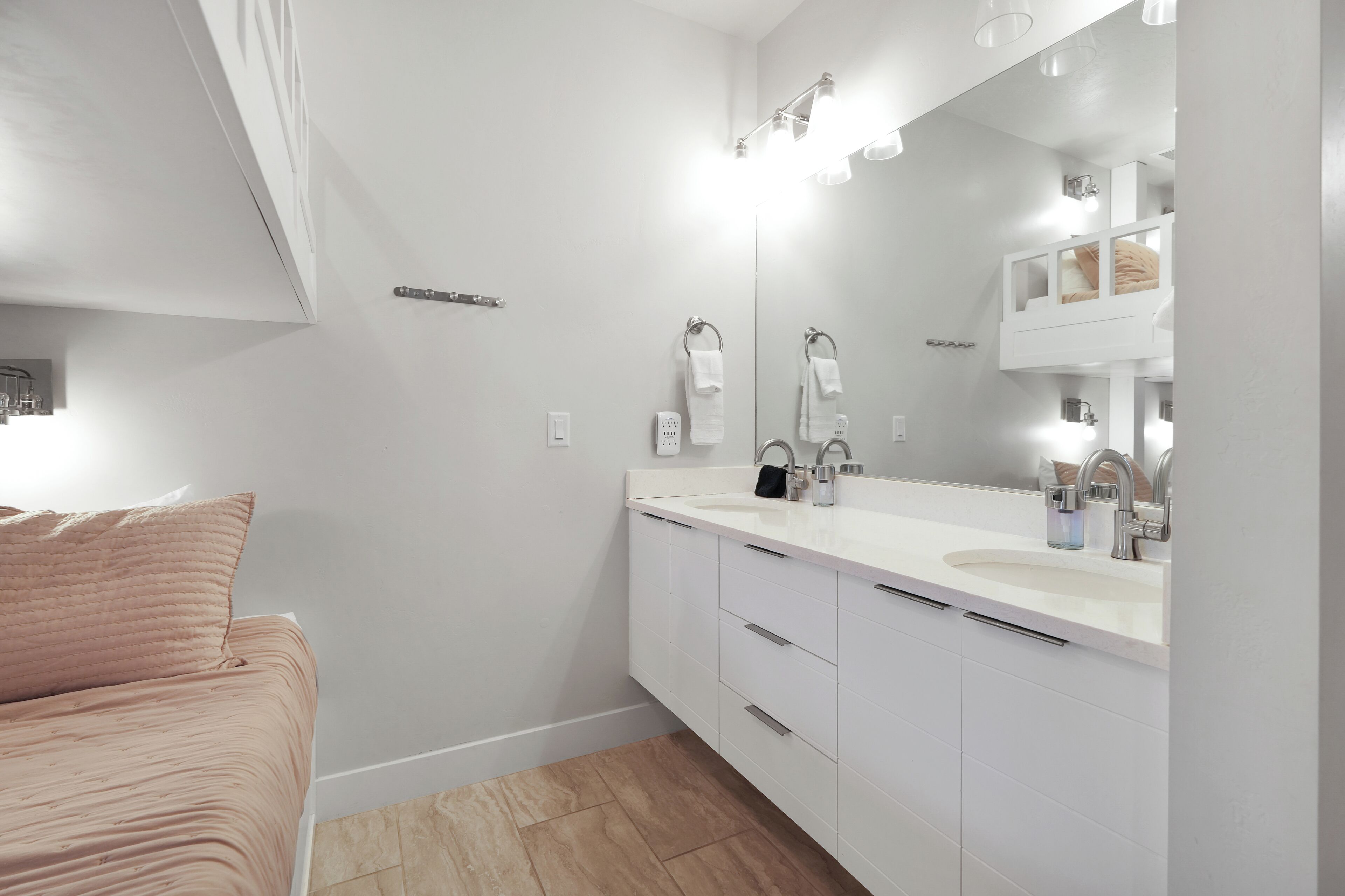 A modern bathroom with a white vanity, a large mirror, and a built-in shelf above the sink.