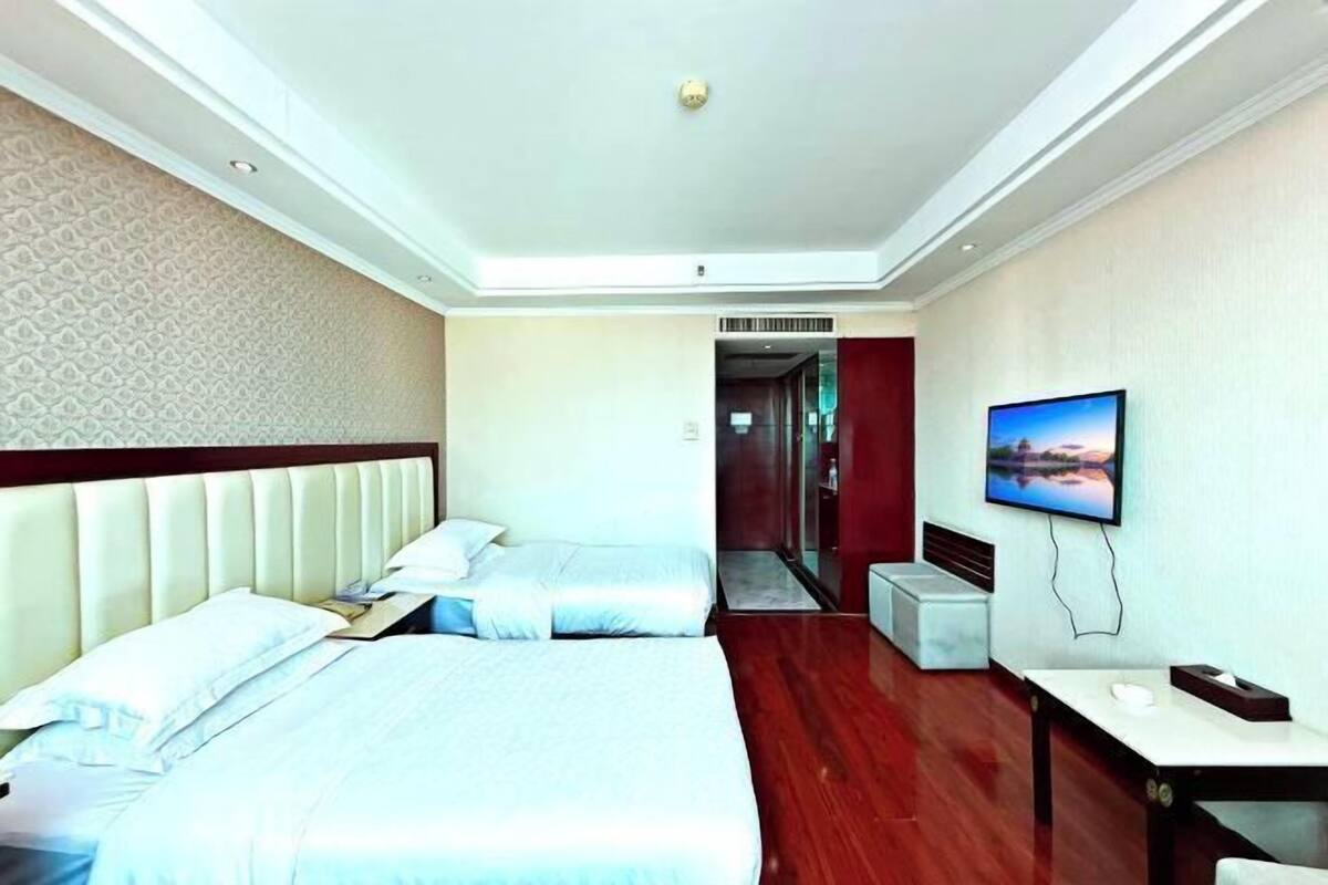 Una habitación de hotel con una cama grande, televisión y una pequeña mesa.