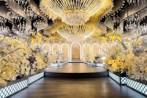 Ein geräumiger Innenraum mit einem offenen Mittelbereich, umgeben von Wänden, die mit floralen Arrangements und einer großen, runden Deckenkonstruktion geschmückt sind.
