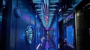 Un passadís amb un disseny futurista, amb elements verticals il·luminats i un sòl reflectant.