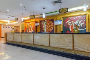 Un área de recepción con mostrador de mármol, arte en la pared, relojes y un cartel.