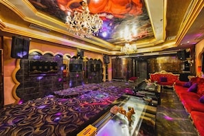 Una habitación lujosa con una cama grande, una zona de estar con un sofá rojo y un candelabro.