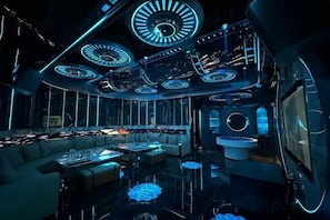 A luxurious interior with a central seating area, multiple circular ceiling lights, and a reflective floor.