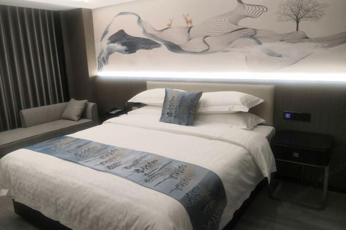 Une chambre d’hôtel moderne avec un grand lit, une table de chevet, une petite table et une œuvre d’art accrochée au mur.