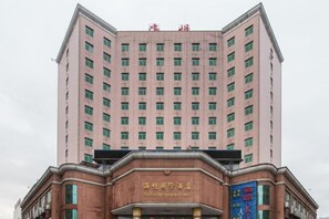Un immeuble hôtelier à plusieurs étages, doté d’une façade rose et d’une enseigne indiquant qu’il s’agit de l’« Hôtel de International ».