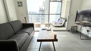 A modern living room with a grey sofa, a wooden coffee table, and a TV. - Appart-Hotel - The sunbath (Annecy)