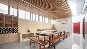 A modern kitchen with wooden benches, a long counter, and a red door. - Dingyi Junyue Hotel (Changde)