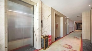 A hotel corridor with marble walls, an elevator, and a patterned carpet. - Dingyi Junyue Hotel (Changde)