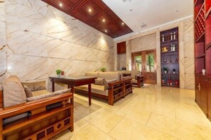 A spacious lobby with marble walls, wooden furniture, and a large bookshelf. - Dingyi Junyue Hotel (Changde)