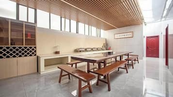 Un interior moderno con área de cocina, bancos de madera y una puerta roja.