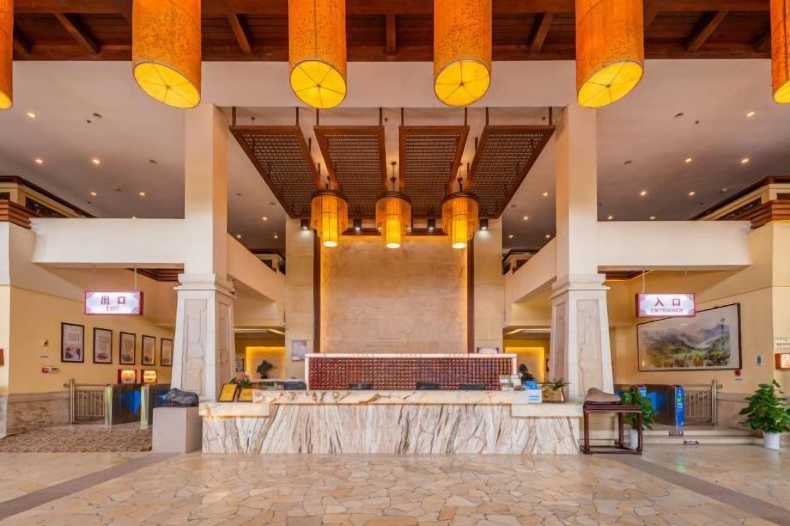A lobby with a reception desk, large columns, and hanging lights.