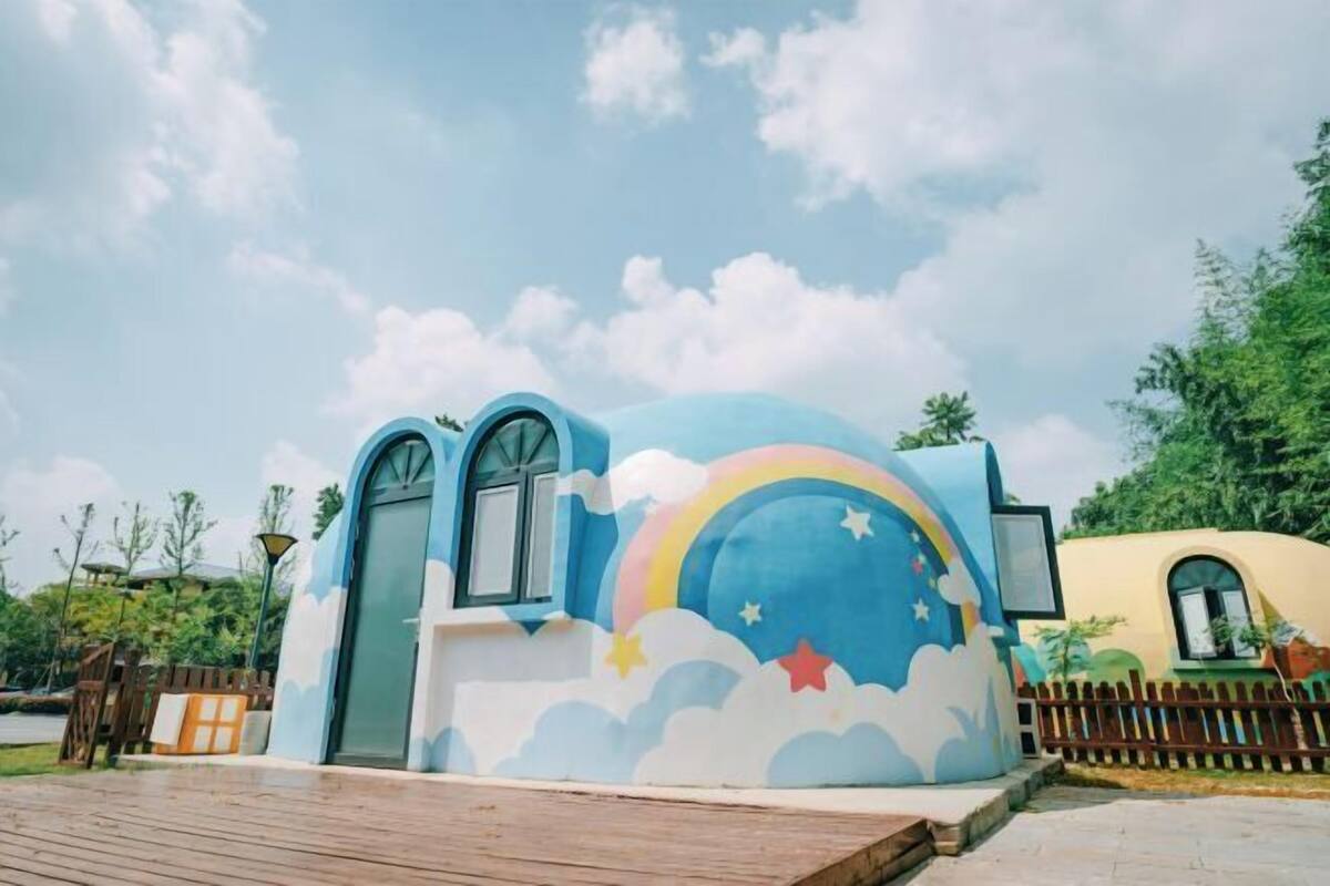 Ein Gebäude mit gewölbtem Dach, Bogenfenstern und einem Wandgemälde von Regenbogen und Wolken.