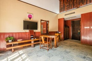 Un vestíbulo con un banco de madera, una mesa, un televisor fijado en la pared y un espejo.