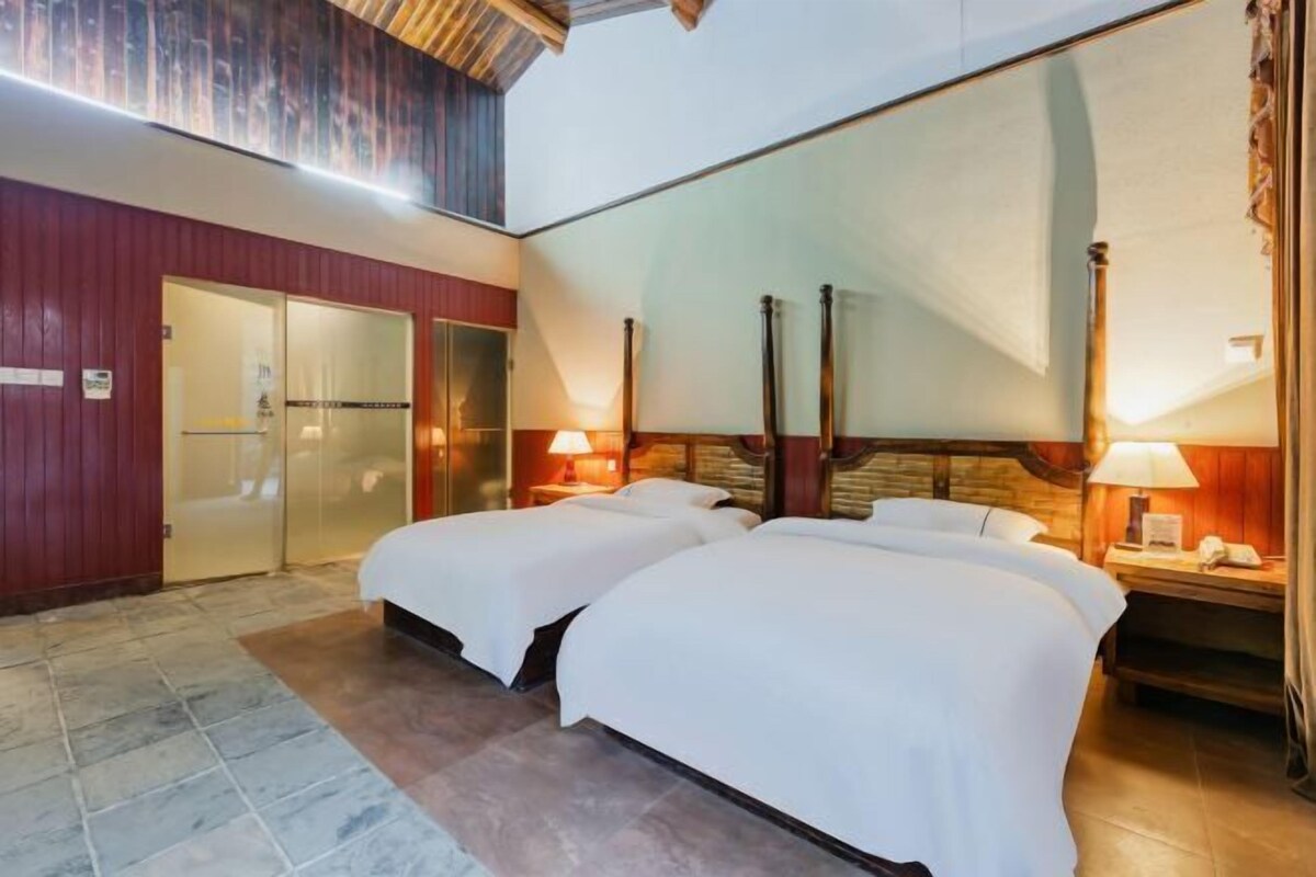 Habitación de hotel con dos camas, techo de madera y un espejo grande.