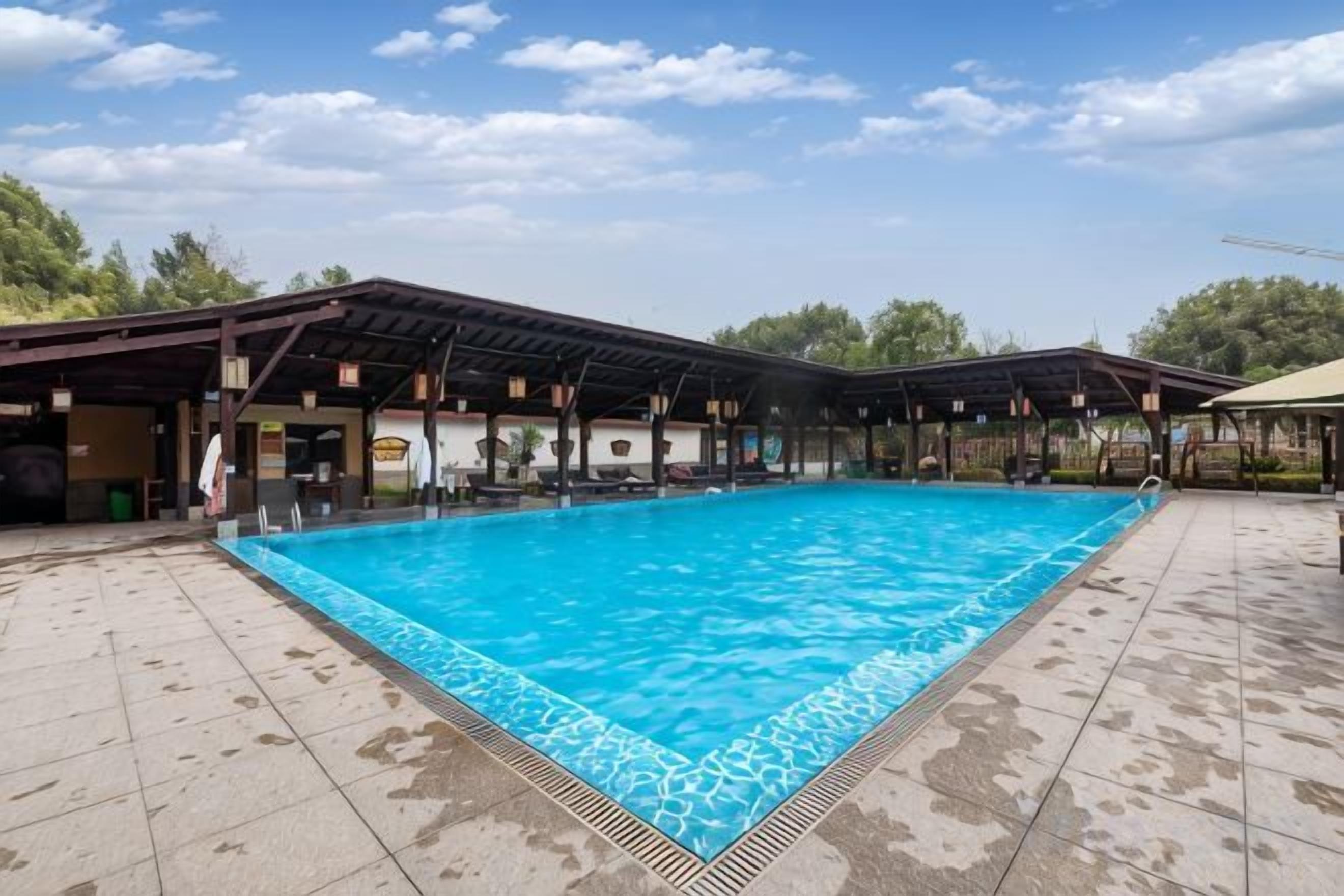 A swimming pool with a covered area and a pavilion, surrounded by a tiled deck.