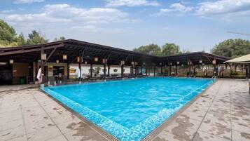 A swimming pool with a covered area and a pavilion, surrounded by a tiled deck.