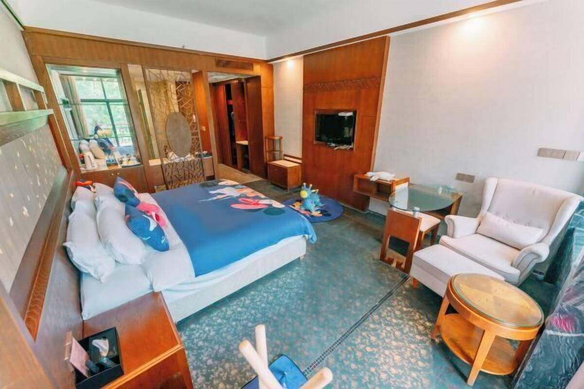 Ein Hotelzimmer mit einem Bett, einer Sitzecke mit Stuhl und Tisch, einem Fernseher und einem Fenster.