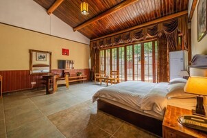 Un dormitorio con techo de madera, cama, escritorio con lámpara y una silla.
