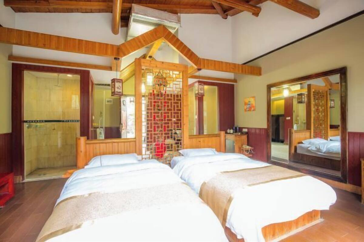 Ein Hotelzimmer mit zwei Betten, einer Holzzieldecke, einem großen Spiegel und einer Schiebetür.
