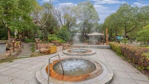 Un área de aguas termales con piscinas circulares, escalones de piedra y vegetación circundante.