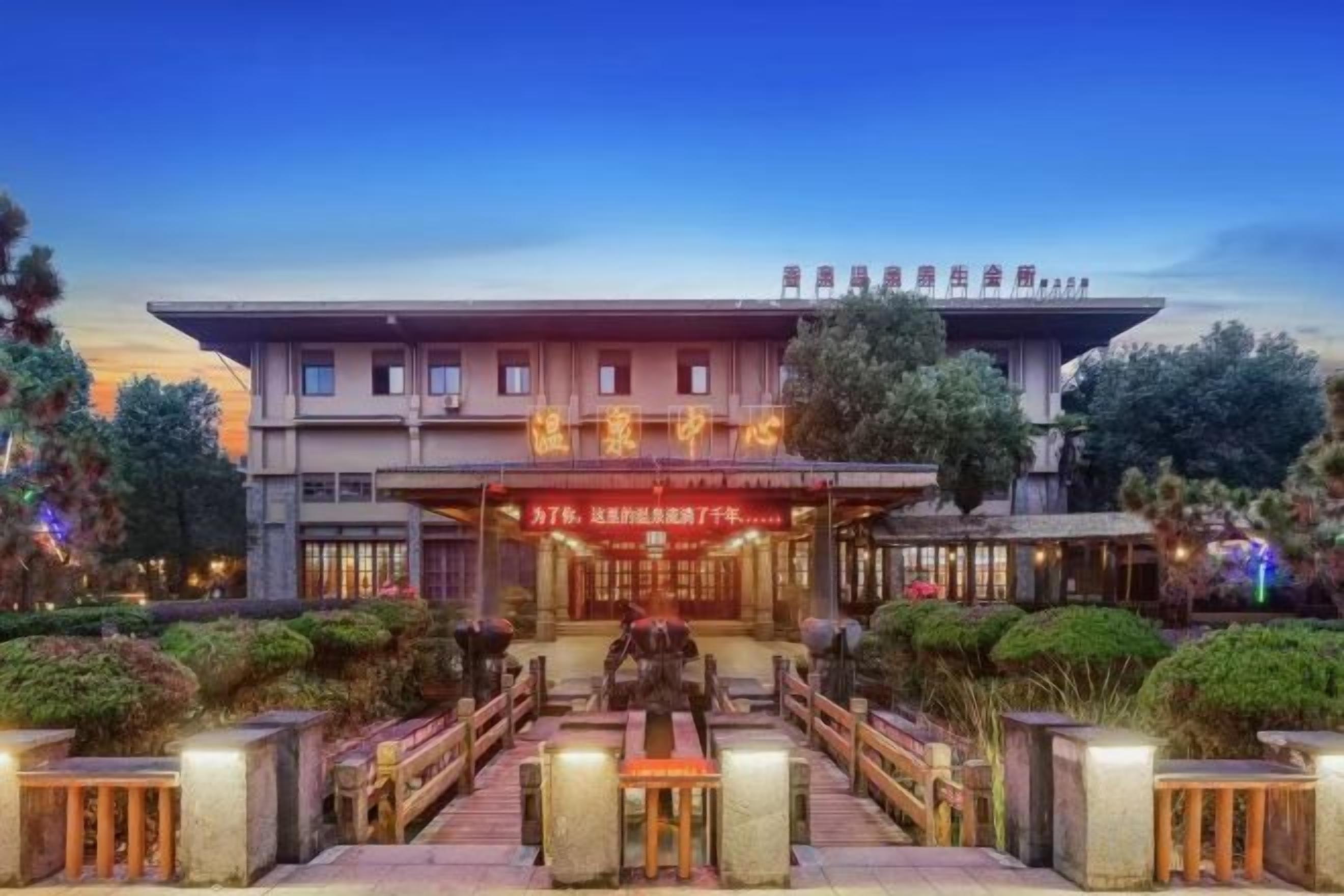 A hotel with a traditional architectural style, featuring a prominent entrance with a sign, outdoor seating area, and well-maintained landscaping.
