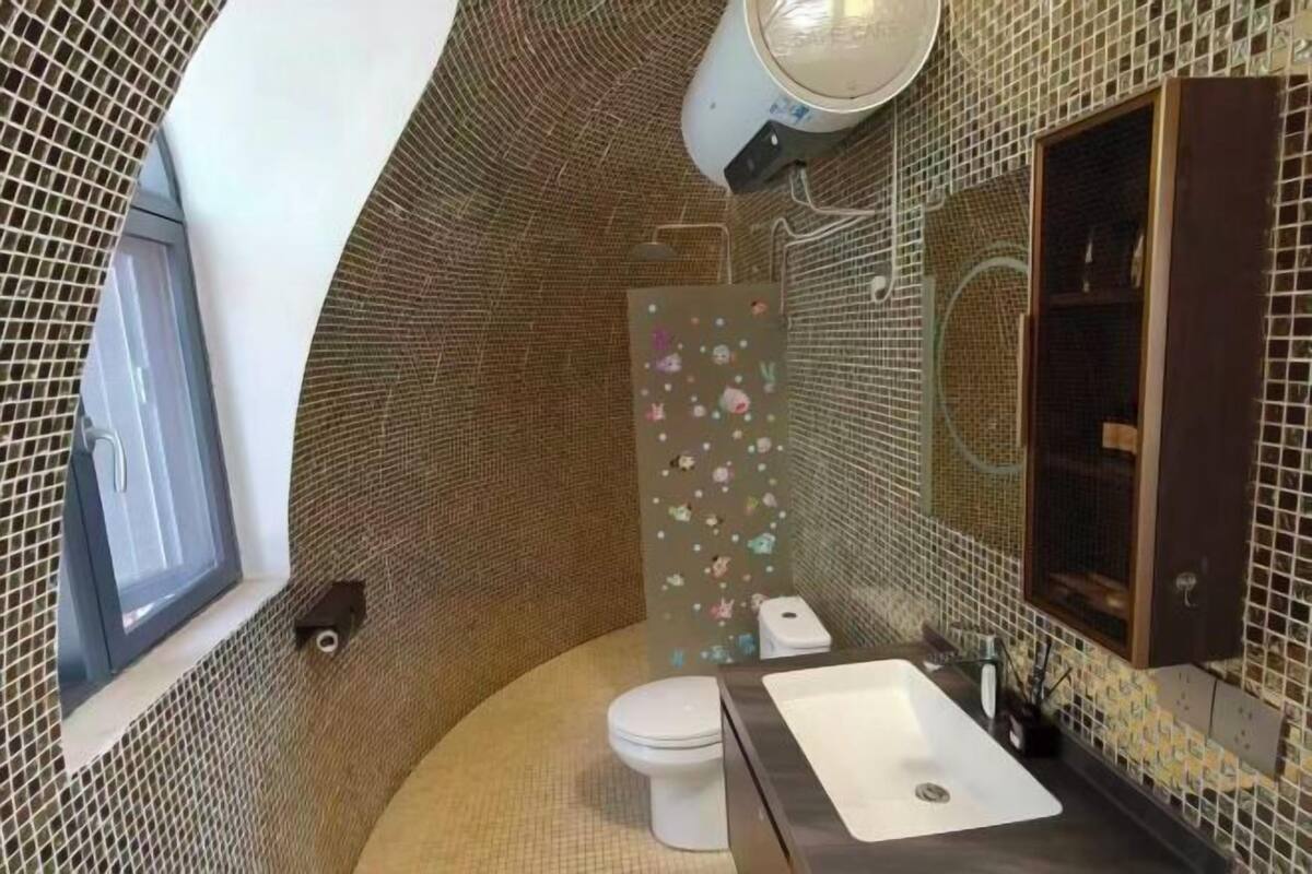 Ein kleines, außergewöhnlich gestaltetes Badezimmer mit gewölbter Decke, Toilette, Waschbecken und Duschkabine.