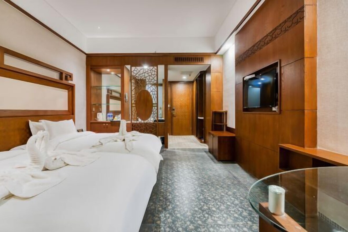 Habitación de hotel con una cama grande, un televisor montado en la pared y paneles de madera en las paredes.