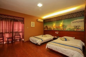 Een hotelkamer met twee bedden, houten vloer, een schilderij aan de muur en een raam met gordijnen.