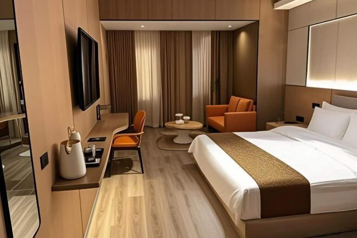 Une chambre d’hôtel comprenant un lit, une télévision, un coin salon avec une table et un canapé.