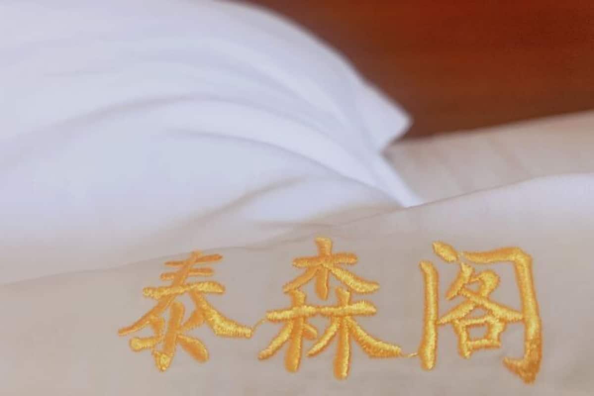 Un tissu blanc orné de caractères chinois dorés brodés.