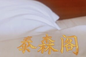 Een witte stof met geborduurd goudkleurig Chinees schrift.