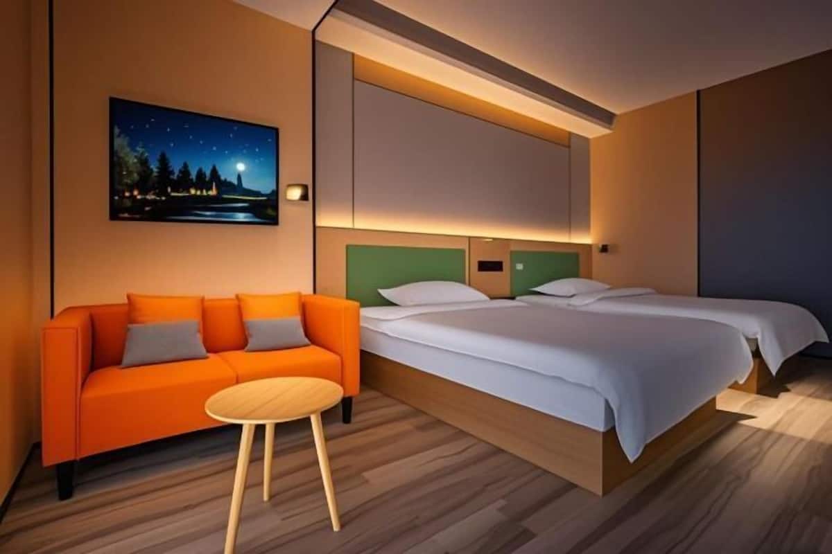 Une chambre d’hôtel avec un lit, un canapé, une petite table ronde et un tableau représentant un ciel étoilé accroché au mur.