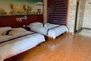 Habitación de hotel con dos camas, piso de madera, un mural en la pared y vistas al exterior.