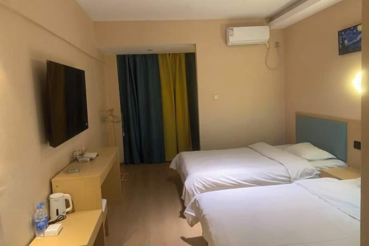Une chambre d’hôtel avec deux lits, une télévision, un bureau avec une bouilloire et un appareil de climatisation.