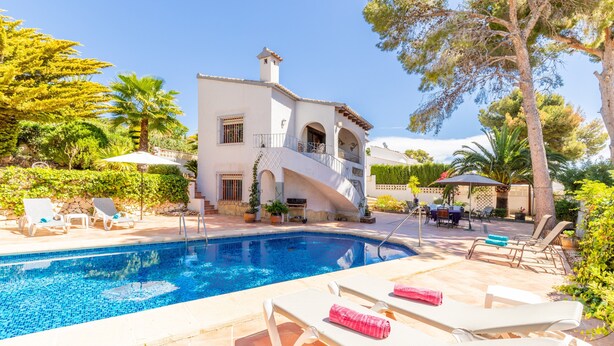 A poolside area with lounge chairs, a pool, and a building with arches and a balcony. - Villa 'Feliz ' with Private Pool, Wi-Fi and Air Conditioning (Calpe)
